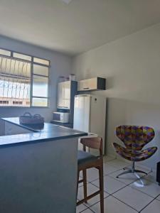 a kitchen with a counter and a refrigerator and a chair at Apartamento inteiro Iguaçu Ipatinga in Ipatinga
