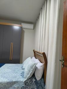 a bedroom with a bed with pillows and a curtain at Apartamento inteiro Iguaçu Ipatinga in Ipatinga