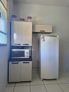 a kitchen with a microwave and a refrigerator at Apartamento inteiro Iguaçu Ipatinga in Ipatinga