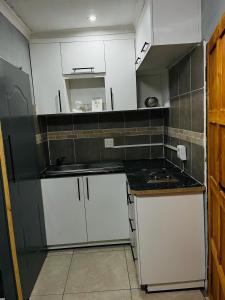 a small kitchen with white cabinets and a sink at Legae la rena in Vosburg