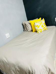 a bed with yellow and white pillows on it at Legae la rena in Vosburg