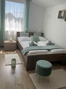 ハイドゥソボスローにあるWhite Stone Apartmanのベッドルーム(大型ベッド1台、青いスツール付)