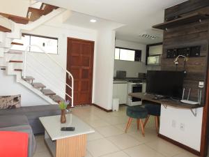 een woonkamer met een bank en een bureau met een computer bij Cobertura Maison dos Colibris in Arraial do Cabo
