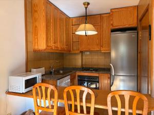 eine Küche mit Holzschränken und einem Holztisch mit Stühlen in der Unterkunft Chimenea en invierno, piscina en verano - Herbasabina 3 in Pla de l'Ermita