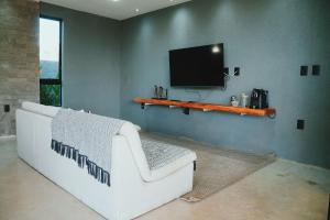 ein Wohnzimmer mit einem weißen Sofa und einem Flachbildfernseher in der Unterkunft Casa em Milagres| 3 suítes, área gourmet, piscina in Passo de Camarajibe