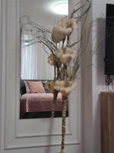 a vase with flowers in front of a mirror at Apartman Karamelica in Užice +10 photos