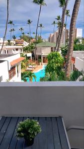 einen Balkon mit Blick auf den Pool und die Palmen in der Unterkunft Punta Cana Beach & Garden B&B 1 in Punta Cana