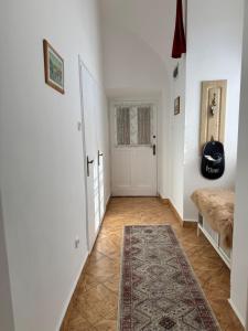 a hallway with white walls and a door and a rug at Forst Apartman in Eger