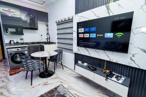 a kitchen with a table and a tv on a wall at Nexus Luxury Apartments in Port Harcourt
