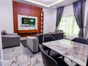 a living room with a table and chairs and a tv at Nexus Luxury Apartments in Port Harcourt