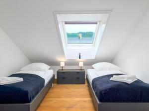 two twin beds in a room with a window at Waldklang - Refugium Schwarzwald in Alpirsbach