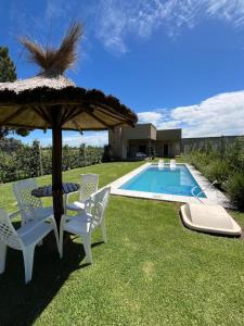 a patio with an umbrella and chairs and a pool at Casa Quinta in Chivilcoy