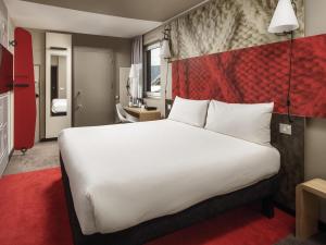 a hotel room with a large bed and a red wall at ibis Coventry Centre in Coventry +58 photos