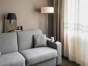 ein Wohnzimmer mit einer Couch und einer Lampe in der Unterkunft Aparthotel Adagio La Défense Esplanade in Puteaux + 51 Fotos