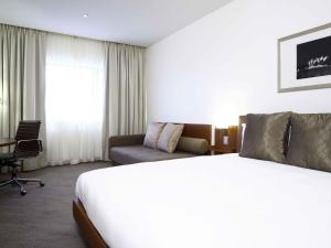 a hotel room with a bed and a couch at Novotel Canberra in Canberra