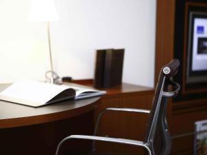 a chair sitting in front of a desk with a book at Novotel Canberra in Canberra
