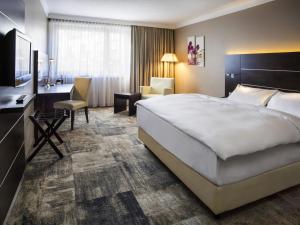 a hotel room with a large bed and a desk at Mercure Hotel Hamm in Hamm +50 photos