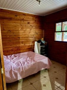 ein Schlafzimmer mit einem Bett und einer Holzwand in der Unterkunft Sítio reservado com piscina in Viamão
