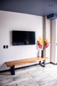 a living room with a bench with a tv and flowers at The Coffee Club Apartahotel in Manizales