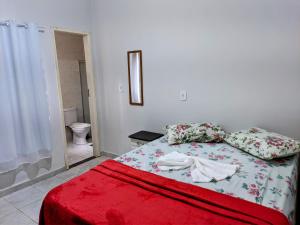 a bedroom with a bed with a red blanket at Pousada mirante do Sol in Piúma