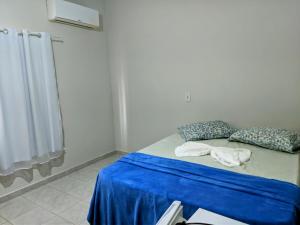 a room with a bed with blue sheets and pillows at Pousada mirante do Sol in Piúma +2 photos