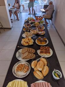 une longue table remplie de différents types de nourriture dans l'établissement Pousada mirante do Sol, à Piúma