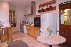 a kitchen with a table and a white refrigerator at Cottage Mackinley, séjour convivial, jeux, grand sapin de Noël, et contes,15 pers, Centre Historique, gare TER in Aubigny-sur-Nère
