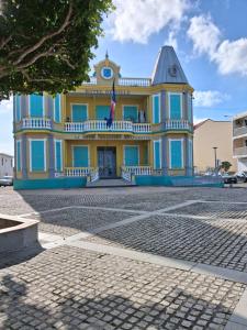 ein gelb-blaues Gebäude mit einer Flagge darauf in der Unterkunft L'IXORA des îles in Le Moule