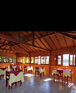 ein Esszimmer mit Tischen und Stühlen und Fenstern in der Unterkunft Chalé Canário da Terra 2 in Visconde De Maua