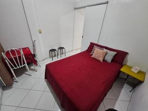 a bedroom with a red bed with a yellow table and chairs at A uma quadra da praia de Copacabana in Rio de Janeiro +2 photos