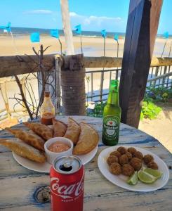 a table with two plates of food and a bottle of soda at Pousada Ventoria in Canguaretama