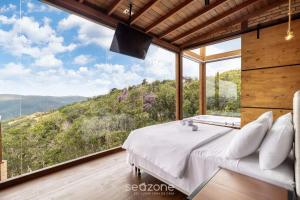 a bedroom with a bed and a large window at Cabana c/ vista panorâmica e jacuzzi - VST026 in São Paulo dos Pinhais +4 photos