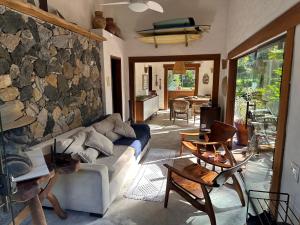 ein Wohnzimmer mit einer Couch und einer Steinwand in der Unterkunft Vila dos Tangarás, Casa 2 Boutique Riacho - 30m do mar in Toque Toque Grande