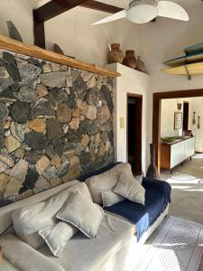 eine Couch in einem Wohnzimmer mit einer Steinwand in der Unterkunft Vila dos Tangarás, Casa 2 Boutique Riacho - 30m do mar in Toque Toque Grande