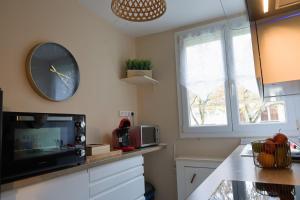 a kitchen with a clock on the wall and a microwave at Le Beauregard, 2 chambres, Hyper Centre de Beauvais in Beauvais +9 photos