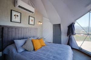 une chambre avec un lit avec des oreillers bleus et jaunes dans l'établissement Cupulas Del Valle by Villa De La Rosa WiFi & AC Suite 2, à San Pablo