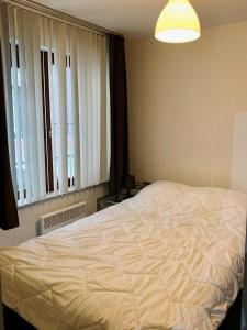 奥斯坦德Relaxed coastal stay - steps from beach & center的卧室里有一张白色的大床和一扇窗户 更多4张照片