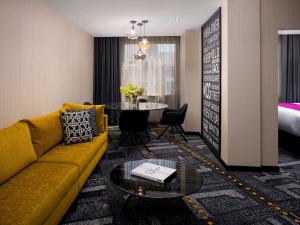 a living room with a yellow couch and a table at Pullman Melbourne City Centre in Melbourne +164 photos