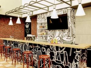 a bar with stools and a black and white wall at Hotel Ibis Łódź Centrum in Łódź