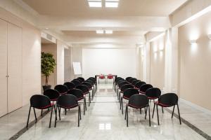 a conference room with black chairs and a white wall at Hotel Olimpia in Imola +39 photos