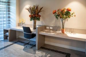a waiting room with two tables with flowers in vases at Hotel Olimpia in Imola