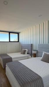 ein Schlafzimmer mit zwei Betten und einem Fenster in der Unterkunft Horizonte do Mar in Apúlia