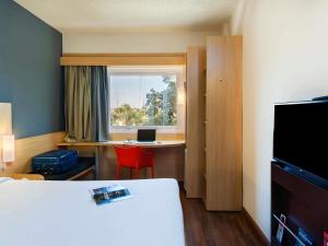 um quarto de hotel com uma cama, uma escrivaninha e uma janela em ibis Paulinia em Paulínia