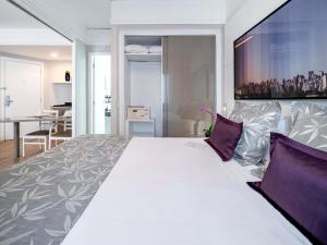 a bedroom with a large white bed with purple pillows at Mercure São Paulo Ibirapuera Privilege in Sao Paulo