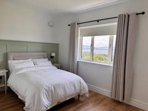 a white bedroom with a large bed and a window at An Chill Bheag At the Blessington Lakes in Blessington