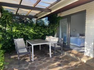 a patio with a table and chairs and a bedroom at Watermill Studios in Gordonʼs Bay