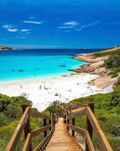 a wooden staircase leading to a beach with blue water at Blue Haven Beach House - Guest Suite I 