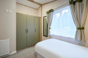 Barmby on the MoorにあるFoxglove Lodge with Hot Tubのベッドと窓のある寝室