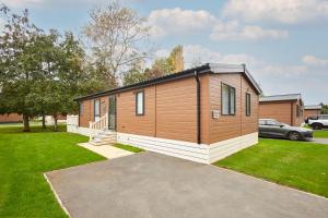 Barmby on the MoorにあるFoxglove Lodge with Hot Tubの駐車場付きの庭にある小さな家