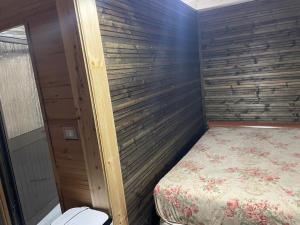 a small bedroom with a bed and a wooden wall at Ohel in Mullini i Danit